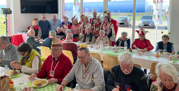 Das Dreigestirn der Karnevalsgesellschaft Rot-Weiß Stürzelberg mit Begleitung und die ehrenamtlich Helfenden (hinten im Bild) begrüßten die Gäste des Seniorenmittagstisches
