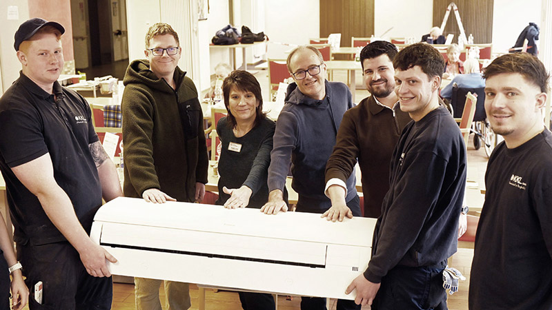 Die KKL-Azubis Moritz Schmelzer (links),  André Schwartz (2.v.r.) und Azubi Milosz Dudzinski (rechts) präsentieren im Theresienheim eine der neuen Klimaanlagen 