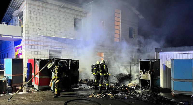 Rollwagen und Container brannten an der Außenfassade eines Geschäftshauses