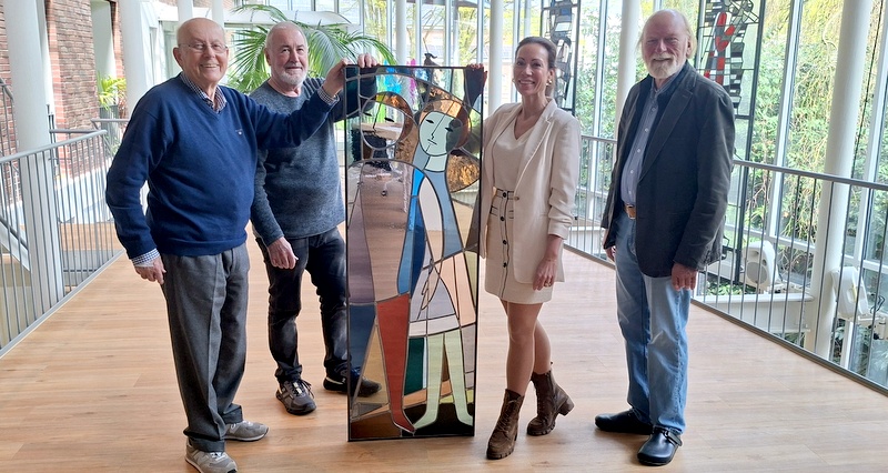 Beispielhaft stellt die Gruppe mit Monografie-Autor Helmut Garritzmann (rechts) ein Glasgemälde von Otto Andreas Schreiber vor